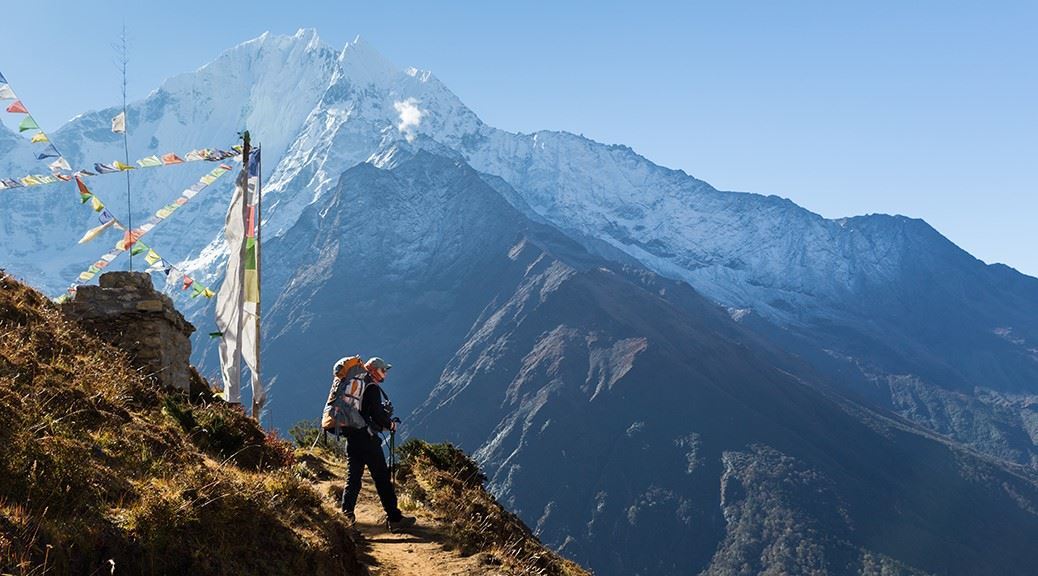 Trekker standing at the edge of the mountain on a trekking track looking at Mount Everest